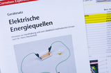 The picture shows instructions for an experiment set on the topic of &quot;Electrical energy sources&quot;. It contains information on handling and didactic use of the device, which is shown with connecting wires and a small bowl.