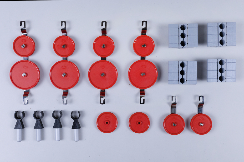 The picture shows an arrangement of red pulleys and gray blocks used in experimental supplies. These components are probably intended for physics experiments to analyze forces and motions.
