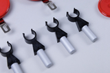 The picture shows several black brackets with silver rods, which are probably used to mount or stabilize experimental equipment. Next to them are red round lids, which could be part of the accessories for teaching in education.