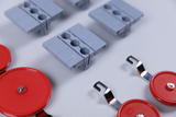 The picture shows various experimental materials, including grey fasteners and red plates with metal hooks. These components are designed for use in educational settings to support experimental activities.