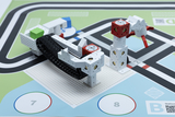 The image shows a construction made of modular building elements that serves as a robotic arm and is positioned on a colored surface. This combination of technology and guidance is ideal for educational experiments.