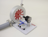 The picture shows an experimental device for demonstrating air pressure and mechanics. It consists of a red wheel, a pressure gauge and a small motor, which together provide an instructive representation of physical principles.