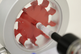The image shows a red-colored experimental device connected to a transparent syringe. It is probably used to conduct physics experiments in education to illustrate various concepts.