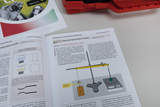 The picture shows a textbook on magnetic properties of materials, which contains instructions for experiments. On one page there is a diagram for carrying out an experiment using a balance and magnetic materials.