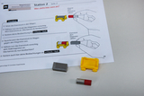 The picture shows materials for an experiment on the topic of magnetism, including instructions on a worksheet. You can see a yellow wagon, various pieces of iron and a magnet, which are to be used for practical experiments.
