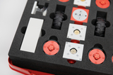 The picture shows a set of several experimental components arranged in a padded container. They are red and white elements, including wheels and connectors, that can be used for various technical experiments in education.