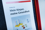 A student kit for experiments on the body and health is shown. It includes various test tubes and samples used to conduct educational experiments.
