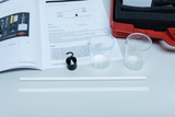 On the table are a textbook and various experimental materials, including two transparent beakers and two white plastic strips. Using the enclosed instructions, students can investigate and observe physical phenomena.