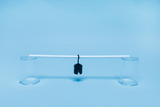 A horizontal tube connects two transparent beakers standing on a blue surface. A black weight hangs from the tube, representing a simple physical experiment setup for demonstrating balance or the laws of levers.