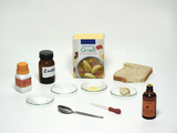 Various ingredients for chemical experiments are arranged on a white background. These include semolina, sugar, starch, a piece of bread, iodine solution, as well as a pipette and a spoon.