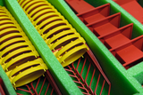 Several yellow and red plastic parts are arranged in a green foam inlay. The yellow parts appear to be round covers, while the red elements function as containers or holders.