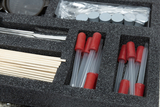 The box contains various experimental supplies, including clear tubes with red stoppers, wooden sticks, and a tool. The arrangement in the foam-padded packaging ensures safe storage and easy access to the materials.