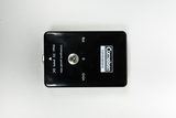 A black experiment device features a connector socket and colored labels in red and green. It is designed for use in schools and supports a maximum voltage of 3 volts DC.