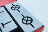 Arranged on a foam-supported surface are several gray plates with black symbols. These plates appear to be designed for experimental educational activities, possibly related to electricity or physics.