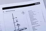 Eine Anleitung zum Thema Wärmeströmung zeigt eine schematische Darstellung eines Versuchsaufbaus. Daneben ist eine detaillierte Materialliste mit benötigten Utensilien wie Kolben und Brenner aufgeführt.